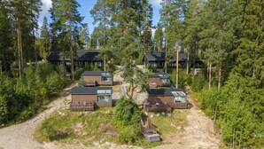 A cluster of cabins surrounded by dense forest, connected by a dirt path. - Koskisviitti 1 (Laukaa)