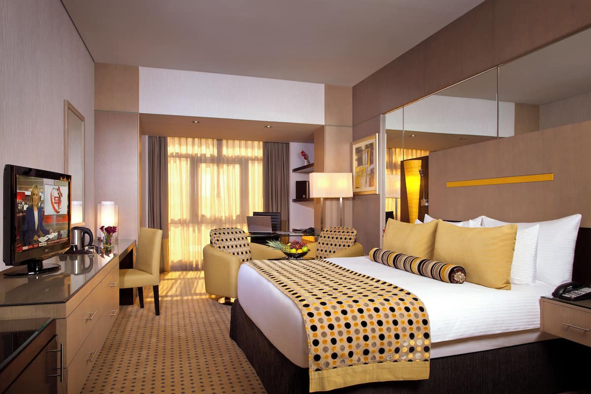 A hotel room with a bed, a desk, a chair, a television, and a mirror.