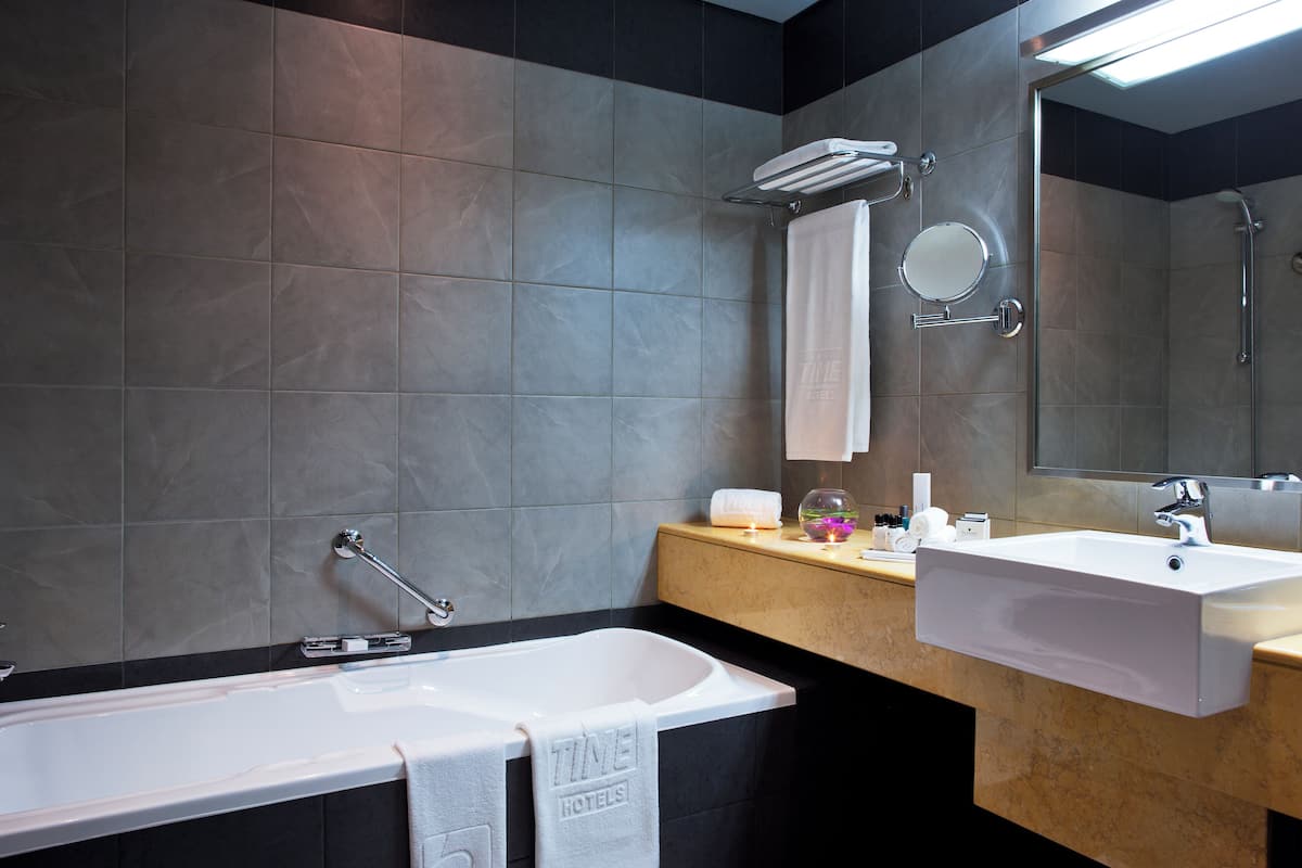 A modern bathroom with a bathtub, a sink, a mirror, and a towel rack.