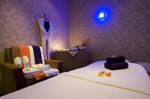 A hotel room with a bed, a chair, a small table with candles, and a wall-mounted light. - Time Grand Plaza (Dubai)
