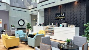 A modern café interior with seating, a counter, and a decorative wall. - Time Grand Plaza (Dubai)