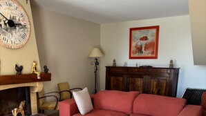 Una sala de estar con un sofá rojo, una mesa de centro de madera, una chimenea y un reloj de pared.