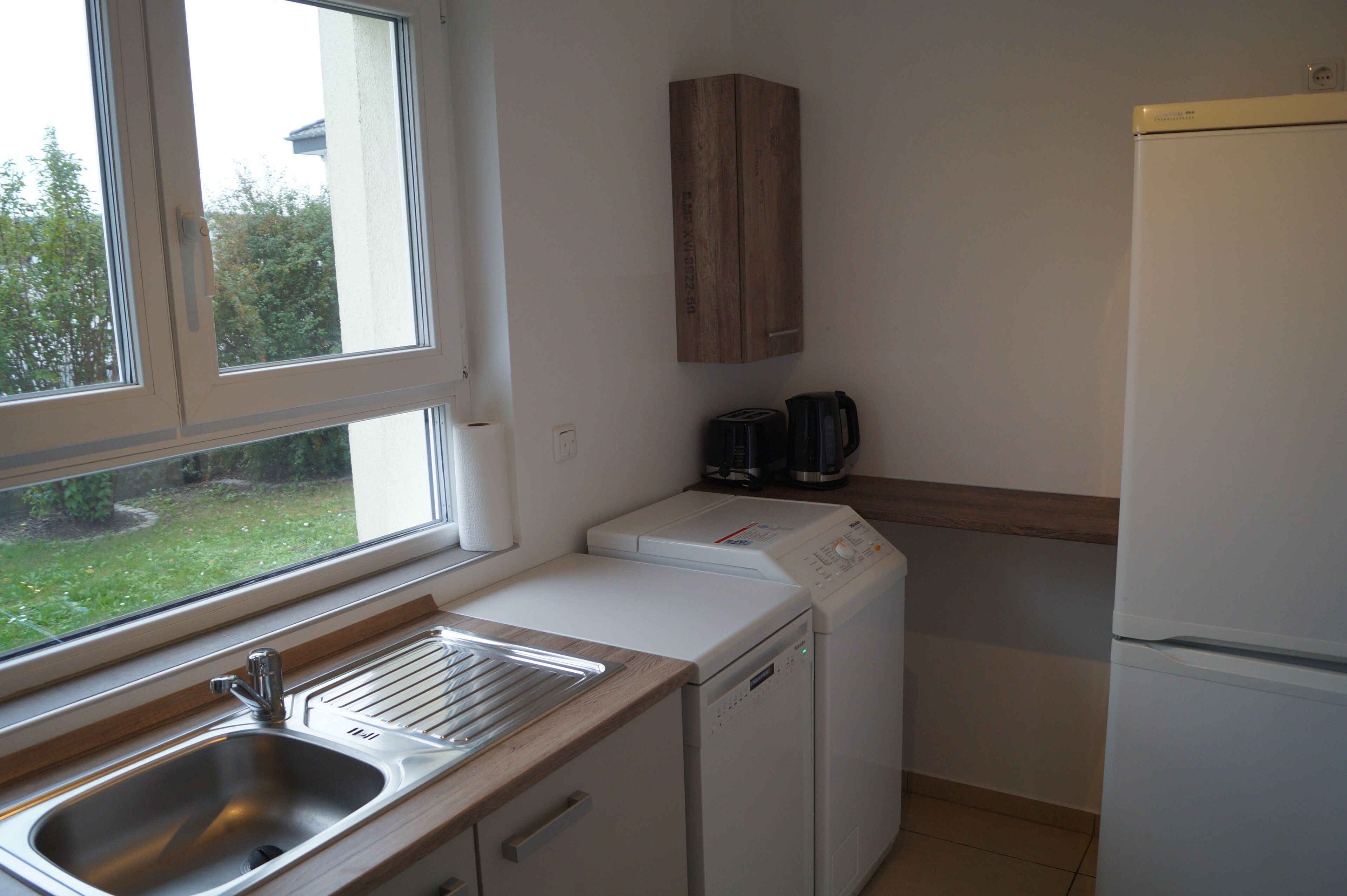 A kitchen with a sink, a dishwasher, a coffee maker, and a refrigerator.