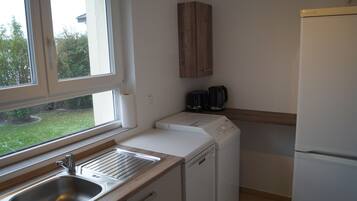 A kitchen with a sink, a dishwasher, a coffee maker, and a refrigerator.