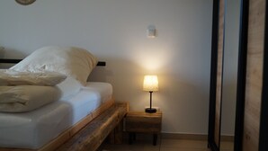 Ett sovrum med en sängram i trä, ett nattduksbord med en lampa och en liten matta på golvet.