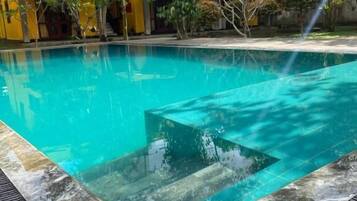 Una piscina al aire libre, sillones reclinables de piscina