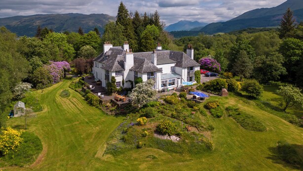 A large white house with multiple chimneys, surrounded by lush greenery and a well-maintained lawn. - Idyllic country suite located at Lonan Country House & Gardens in Scotland! (Taynuilt)