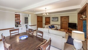 A modern living room with a dining table, sofa, and TV. - Idyllic country suite located at Lonan Country House & Gardens in Scotland! (Taynuilt)