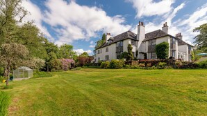 A large, two-story house with a well-maintained lawn and a greenhouse. - Idyllic country suite located at Lonan Country House & Gardens in Scotland! (Taynuilt)