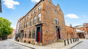 A historic brick building with multiple windows, a red door, and a cobblestone street. - Friargate House -  a premium stay that sleeps 9 guests  in 4 bedrooms (York)