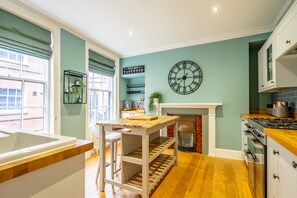 A kitchen with a clock, a coffee menu sign, and a fireplace. - Friargate House - a premium stay that sleeps 9 guests in 4 bedrooms (York)