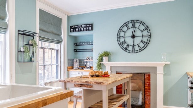 A kitchen with a wooden table, a clock, and a coffee menu sign on the wall. - Friargate House -  a premium stay that sleeps 9 guests  in 4 bedrooms (York)