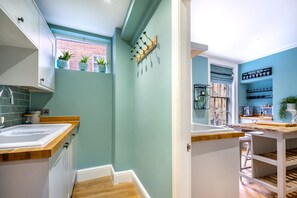 Une petite cuisine étroite avec une fenêtre, un évier et un coin café.