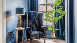 A corner room with a dark blue armchair, a lamp, and a potted plant. - Friargate House -  a premium stay that sleeps 9 guests  in 4 bedrooms (York)