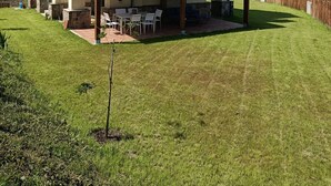 Een huis met twee verdiepingen, een dak met rode tegels, een stenen schoorsteen en een overdekt terras met tuinmeubilair.