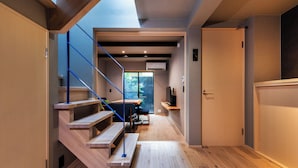 Un interior moderno con una escalera de madera, un comedor y vistas a través de un ventanal.