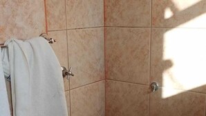 A corner shower with beige tiles and a visible towel rack. - Hotel Palace Huesca (Presidente Prudente)