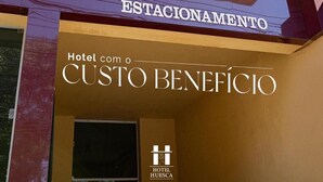 The exterior of Hotel Huesca with the sign 'Hotel com o Custo Benefício' and 'Hotel Huesca' logo. - Hotel Palace Huesca (Presidente Prudente)