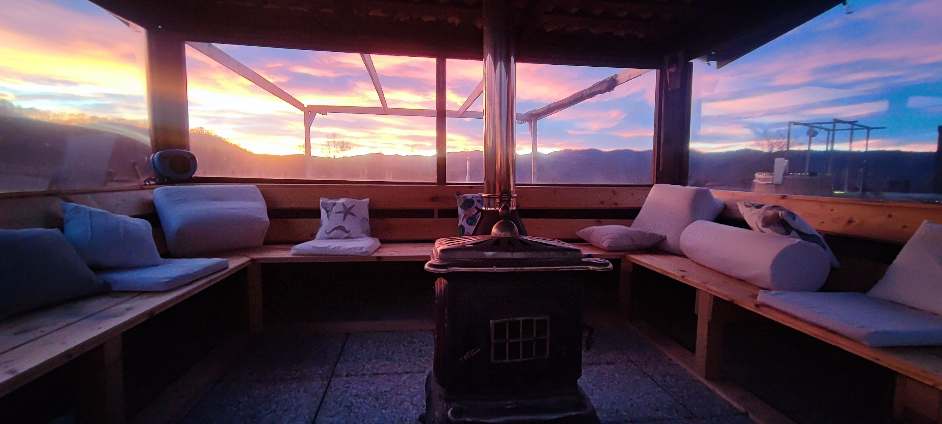 A cozy room with wooden benches and a large window overlooking a mountainous landscape.