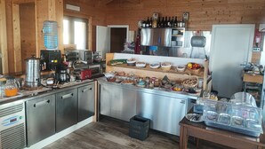 A rustic kitchen with wooden walls, stainless steel appliances, and a variety of food items and condiments on the counter.