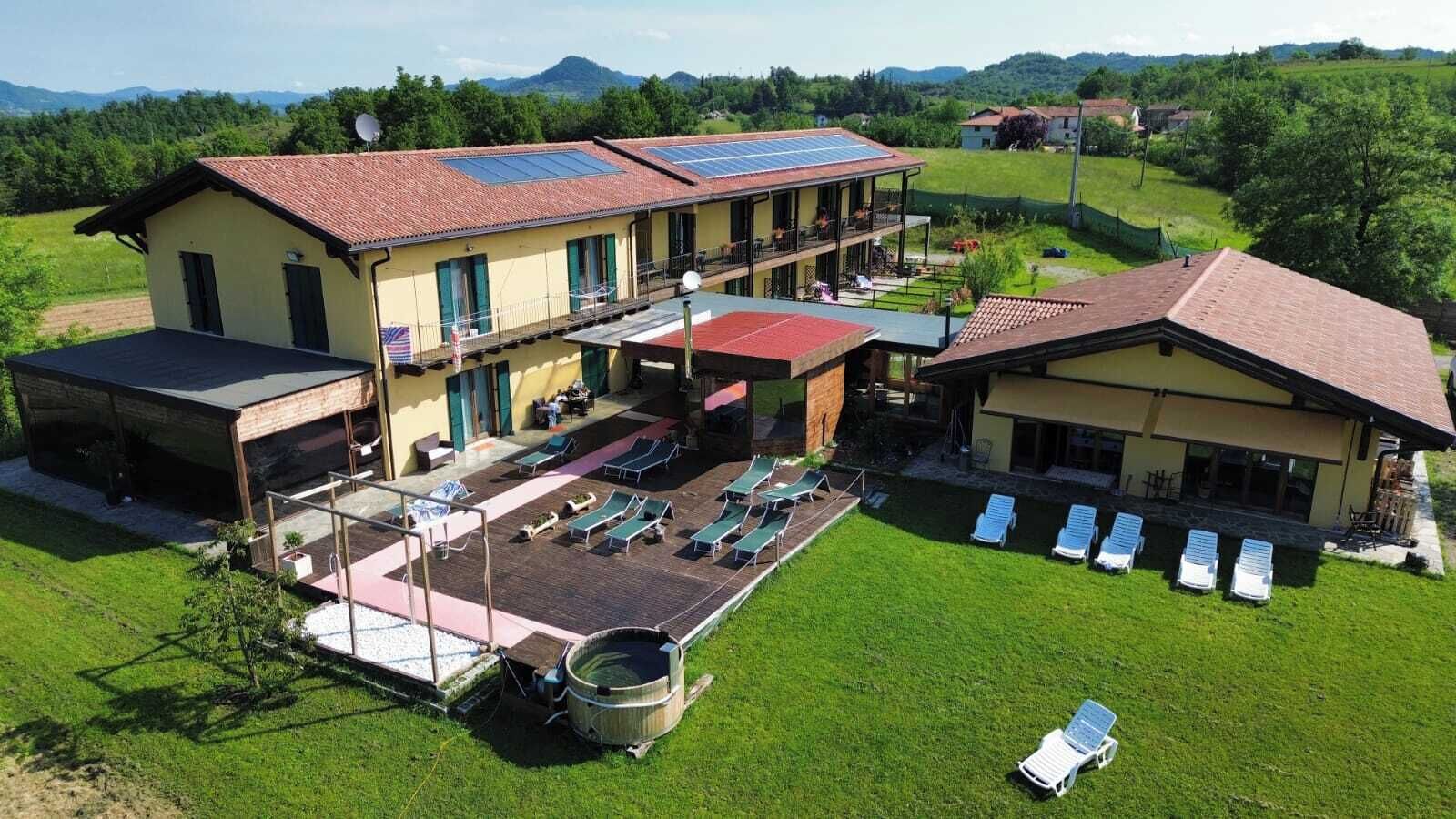 A hotel with a swimming pool, sun loungers, and a covered outdoor area.