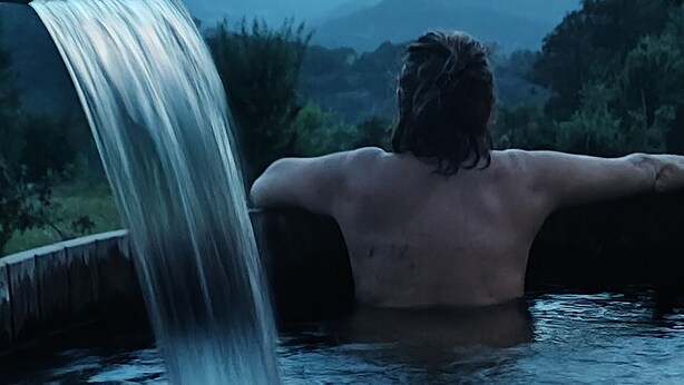 A person relaxing in a hot tub with a waterfall.