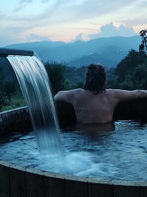 A person relaxing in a hot tub with a waterfall.