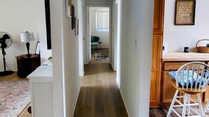 Un pasillo que lleva a un comedor con cocina, un ventilador y una cita enmarcada en la pared.