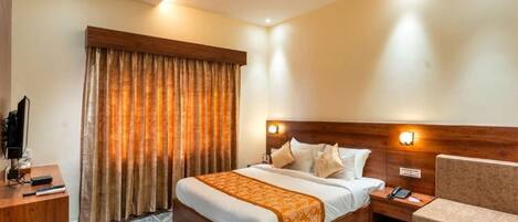 A hotel room with a bed, bedside table, and a chair.