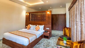 A hotel room with a large bed, a nightstand, a chair, and a decorative wall panel. - The Grand Fateh (Udaipur)