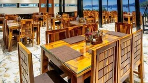 A spacious dining area with wooden tables and chairs, a patterned floor, and a ceiling with recessed lighting. - The Grand Fateh (Udaipur)