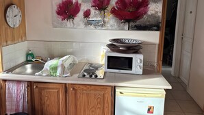 Una cucina con mobili in legno, un forno a microonde, un lavandino e un quadro decorativo sopra il bancone.