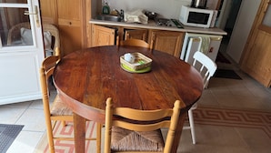 Un tavolo da pranzo in legno con sedie, un angolo cottura con un forno a microonde e un cesto sul tavolo.