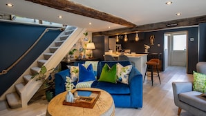 Un salon moderne avec un canapé bleu, une table basse et un escalier doté d’une rampe en corde.