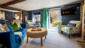 Un salon moderne avec un canapé bleu, une table basse ronde en bois et un fauteuil à motifs.
