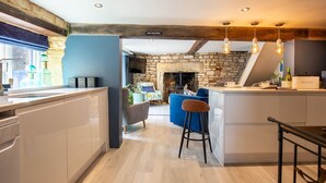 Une cuisine moderne avec une cheminée en pierre, un coin bar et une vue sur le salon.