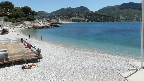 A pebble beach with a wooden deck and a lifeguard tower.