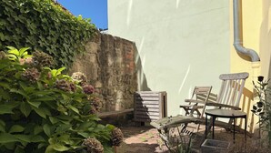 A patio with a brick floor, a wooden bench, a chair, and potted plants. - DREAMZzz AltstadtJuwel in the city center of Coburg I at the market square & parking garage (Coburg)
