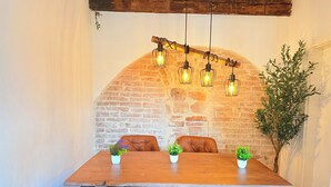 A dining area with a brick wall, wooden table, leather chairs, hanging light fixtures, and potted plants. - DREAMZzz AltstadtJuwel in the city center of Coburg I at the market square & parking garage (Coburg)
