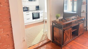 A modern kitchen with white cabinets, a microwave, oven, and a large TV on a wooden stand. - DREAMZzz AltstadtJuwel in the city center of Coburg I at the market square & parking garage (Coburg)