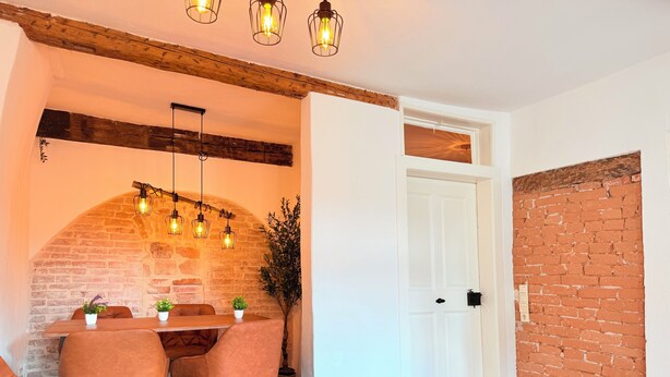 A cozy dining area with a brick wall, wooden ceiling beams, and a table with chairs. - DREAMZzz AltstadtJuwel in the city center of Coburg I at the market square & parking garage (Coburg)