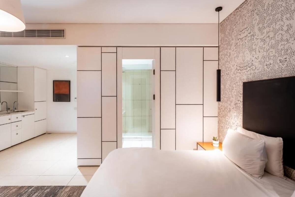 Ein modernes Schlafzimmer mit einem großen Bett, einem begehbaren Kleiderschrank und einem Badezimmer mit Glastür.
