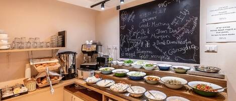 A buffet setup with various dishes and a chalkboard menu.