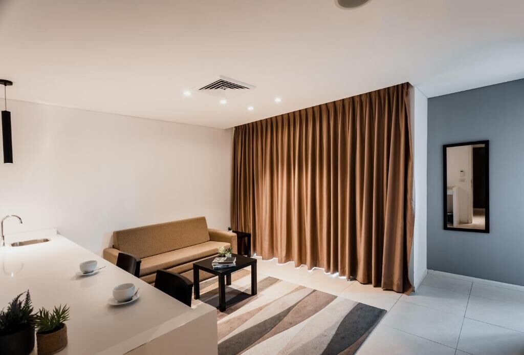 Una sala de estar moderna con un sofá, una mesa de centro y un comedor con una mesa y sillas blancas.