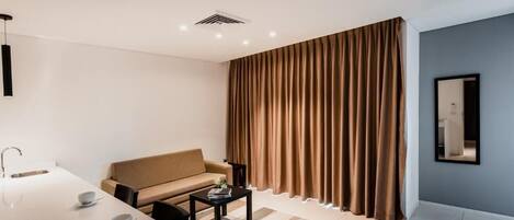 Una sala de estar moderna con un sofá, una mesa de centro y un comedor con una mesa y sillas blancas.