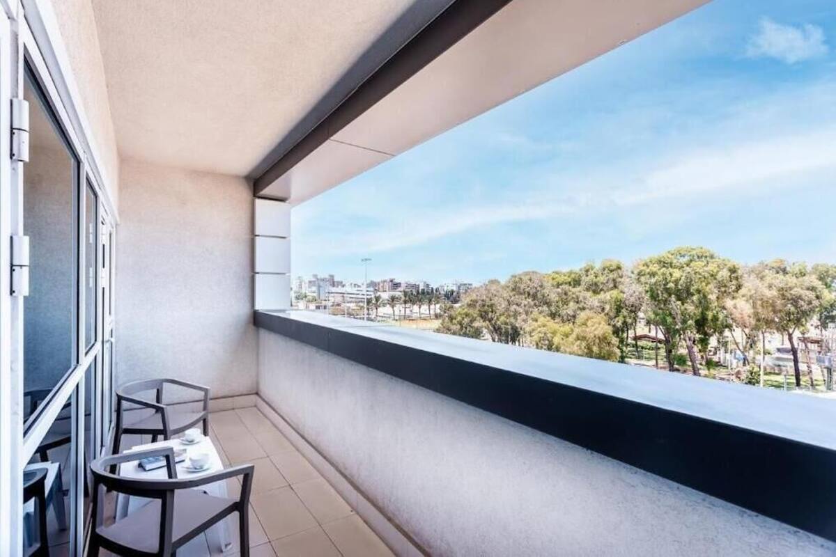 Ein Balkon mit Blick auf eine Stadtlandschaft und Bäume.