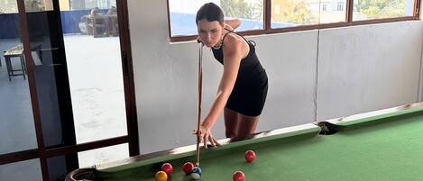 A pool table with balls, a window, and a view of the outside.