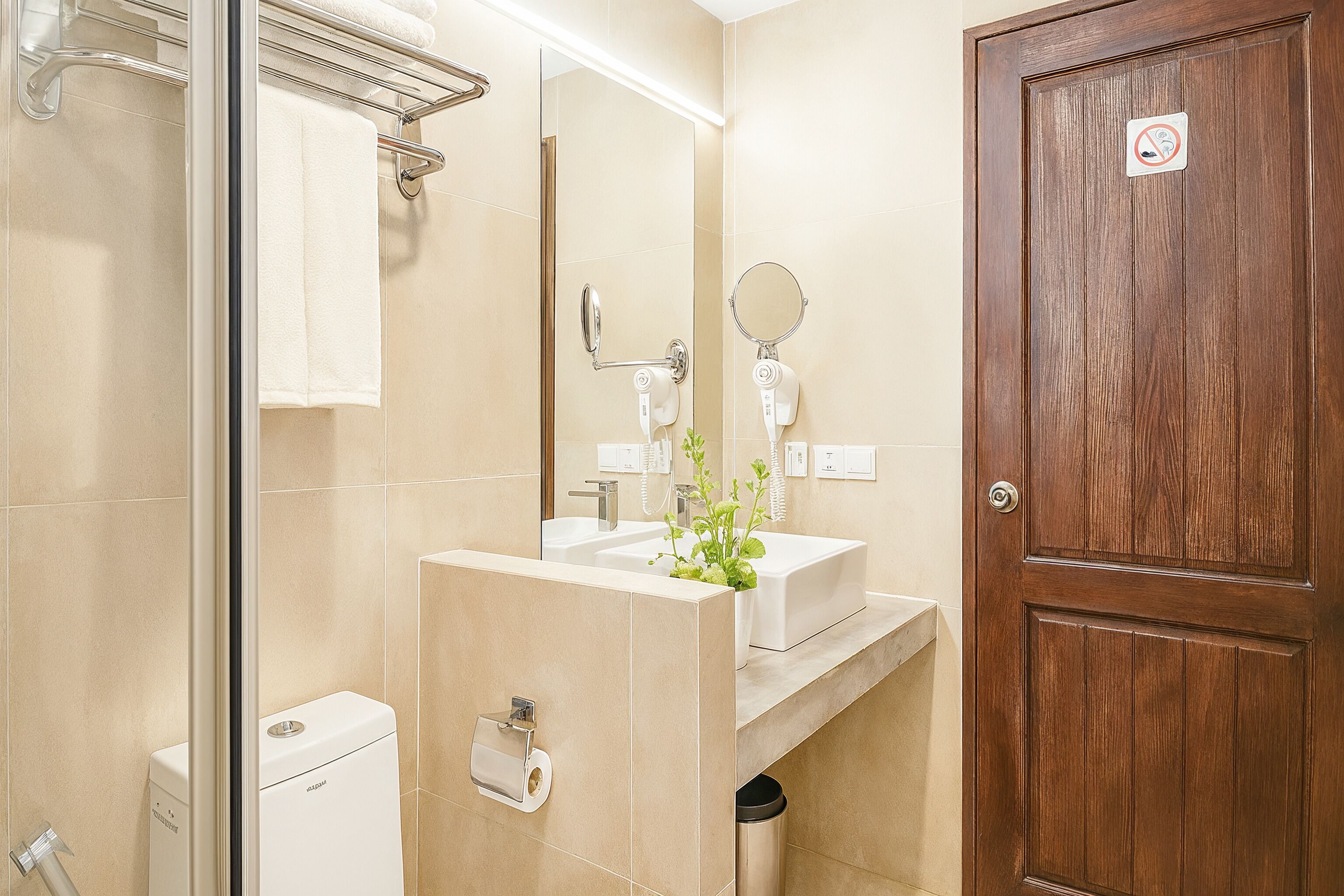 A modern bathroom with a glass shower enclosure, a white sink, and a wooden door.