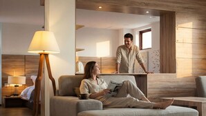 Habitació d'hotel moderna amb sofà, làmpada d'estat, terra de fusta i un mirall gran.