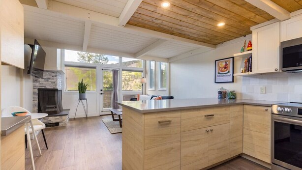 A modern kitchen with a central island, built-in appliances, and a view to the outside. - Modern Condo with Vail Mountain Views (Vail)